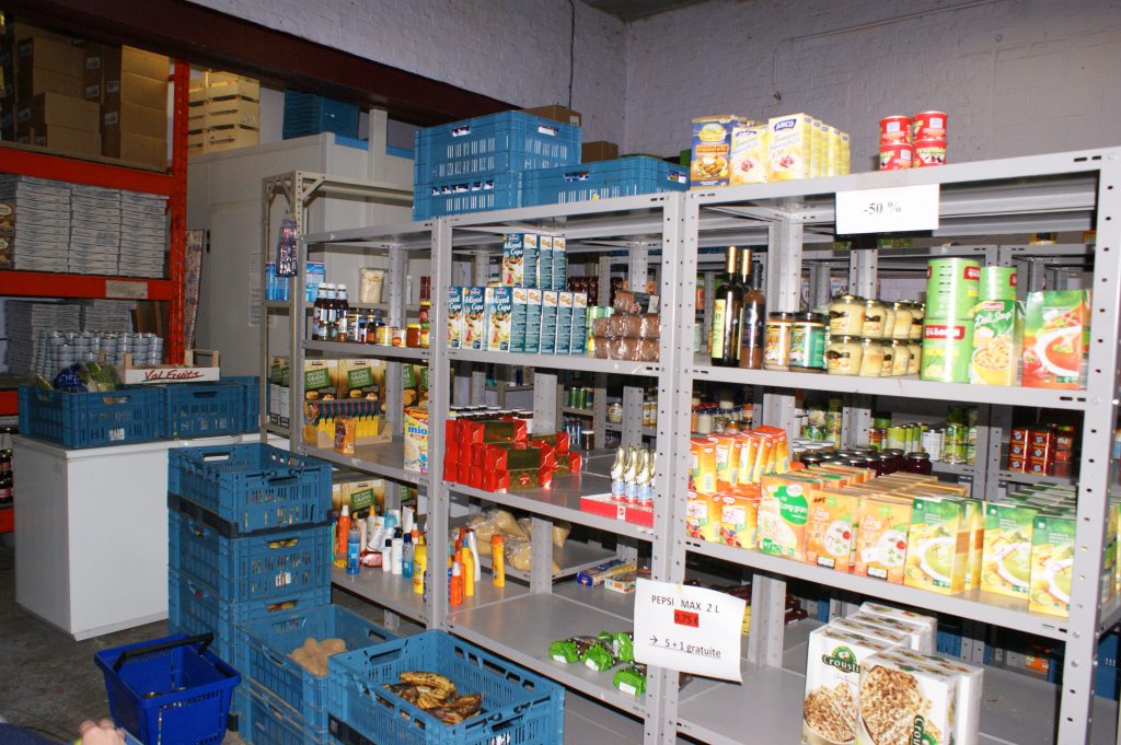 Une salle de stockage avec des étagères pleines d'aliments emballés dans des boîtes, des bouteilles, des bocaux, etc.