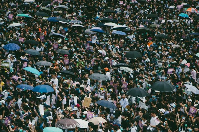 Une foule de gens manifestant, certains portent des parapluies, d’autres des affiches.