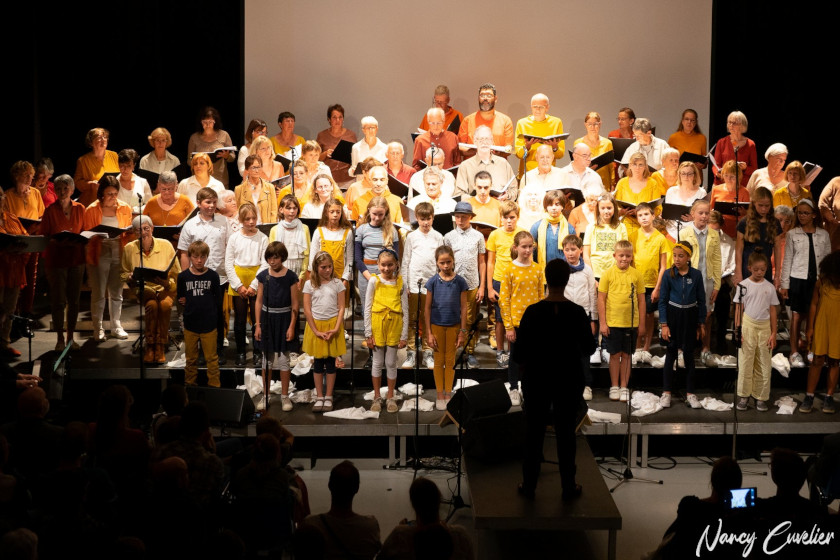 Photo d'une grande chorale d'adultes en d'enfants sur scène