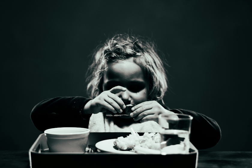 Un enfant devant un repas, en train de manger avec les mains