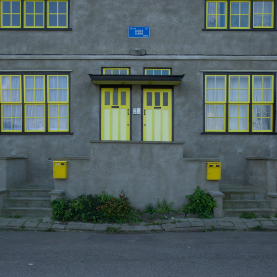 Bâtiment en béton gris avec porte et fenêtres jaunes