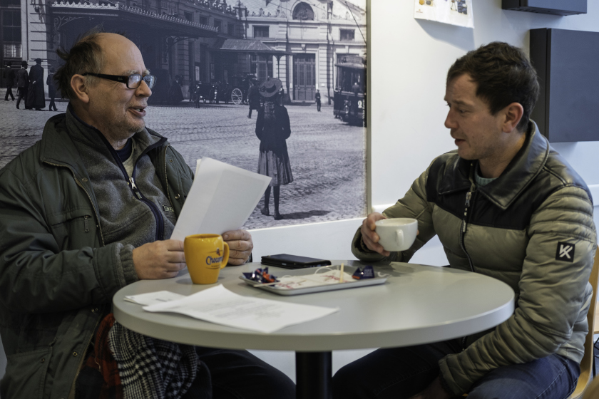 Deux personnes prennent un café et se penchent au dessus de papiers