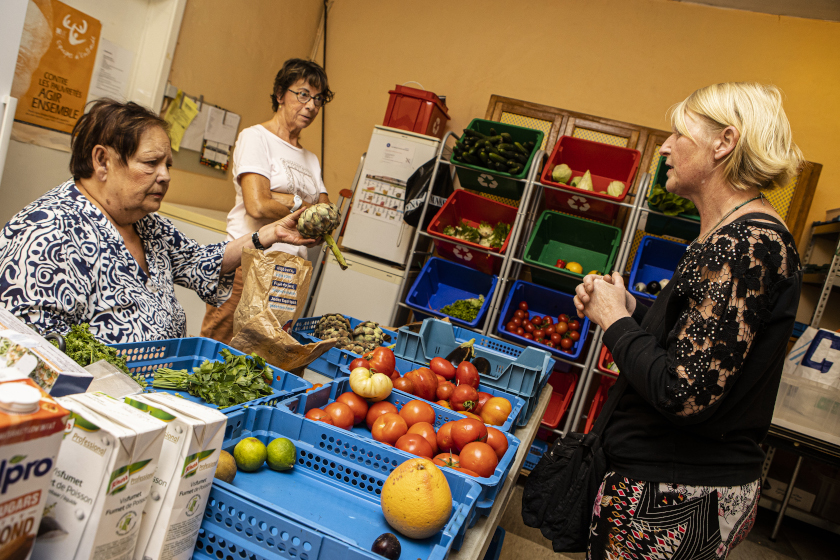 3 personnes s'échangeant autour de cagettes remplies de de fruits et légumes frais
